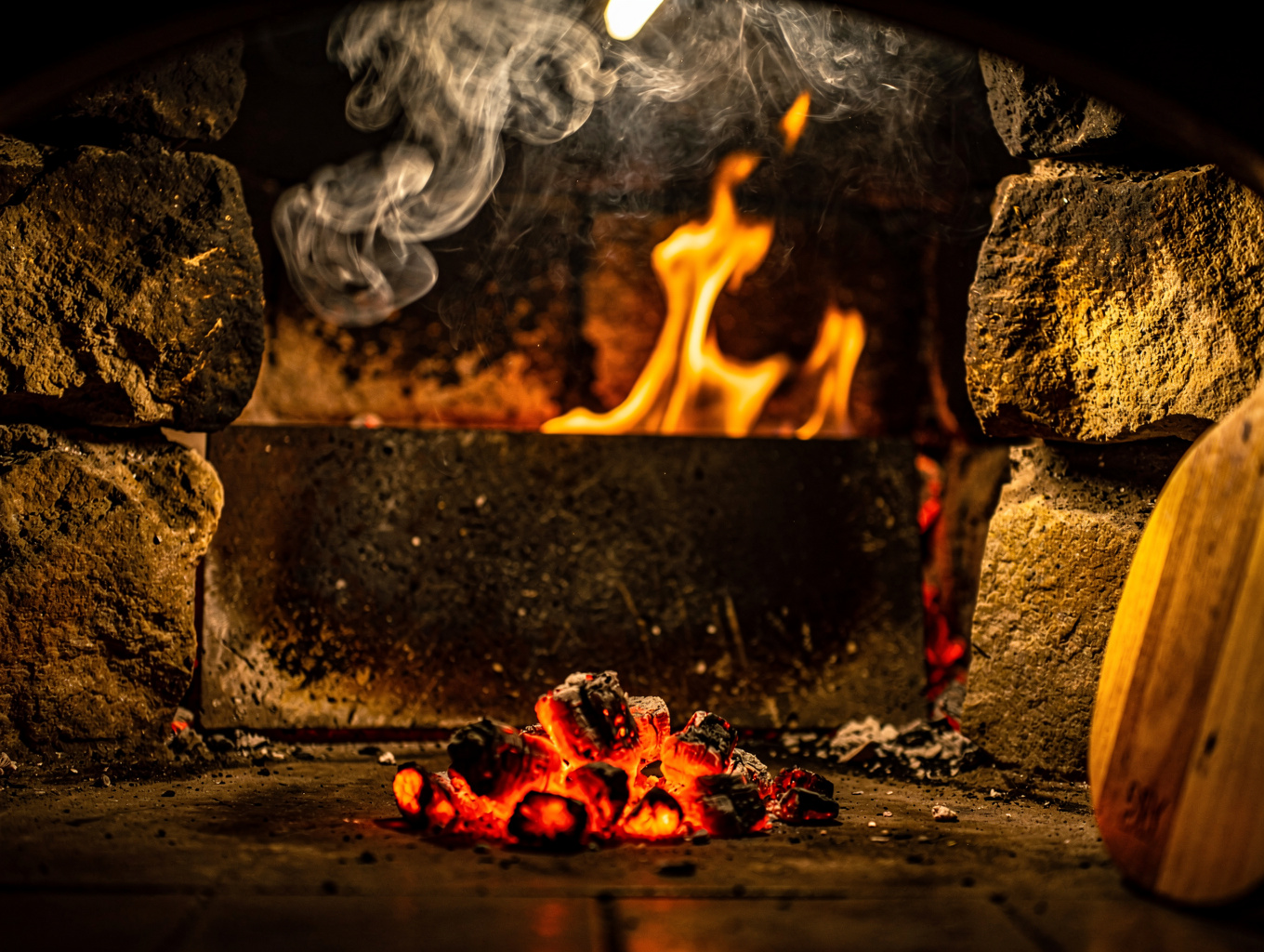 Glowing embers and flames inside a professional wood-fired oven